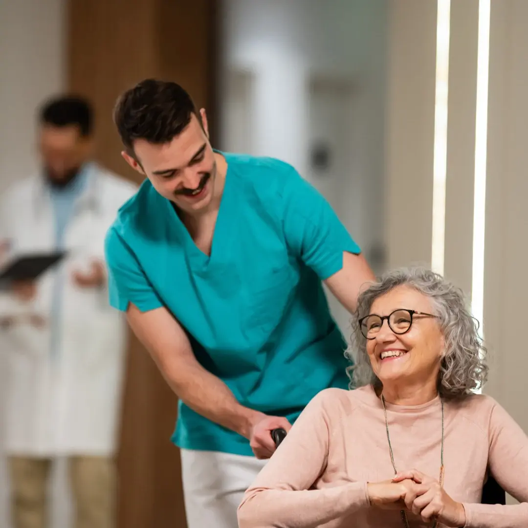 Maennliche Pflegekraft mit Dame im Rollstuhl